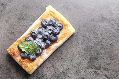 Tasty puff pastry with blueberries and mint on grey table, top view. Space for text