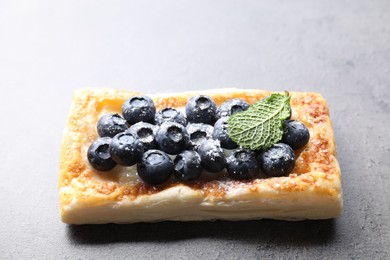 Photo of Tasty puff pastry with blueberries and mint on grey table, closeup