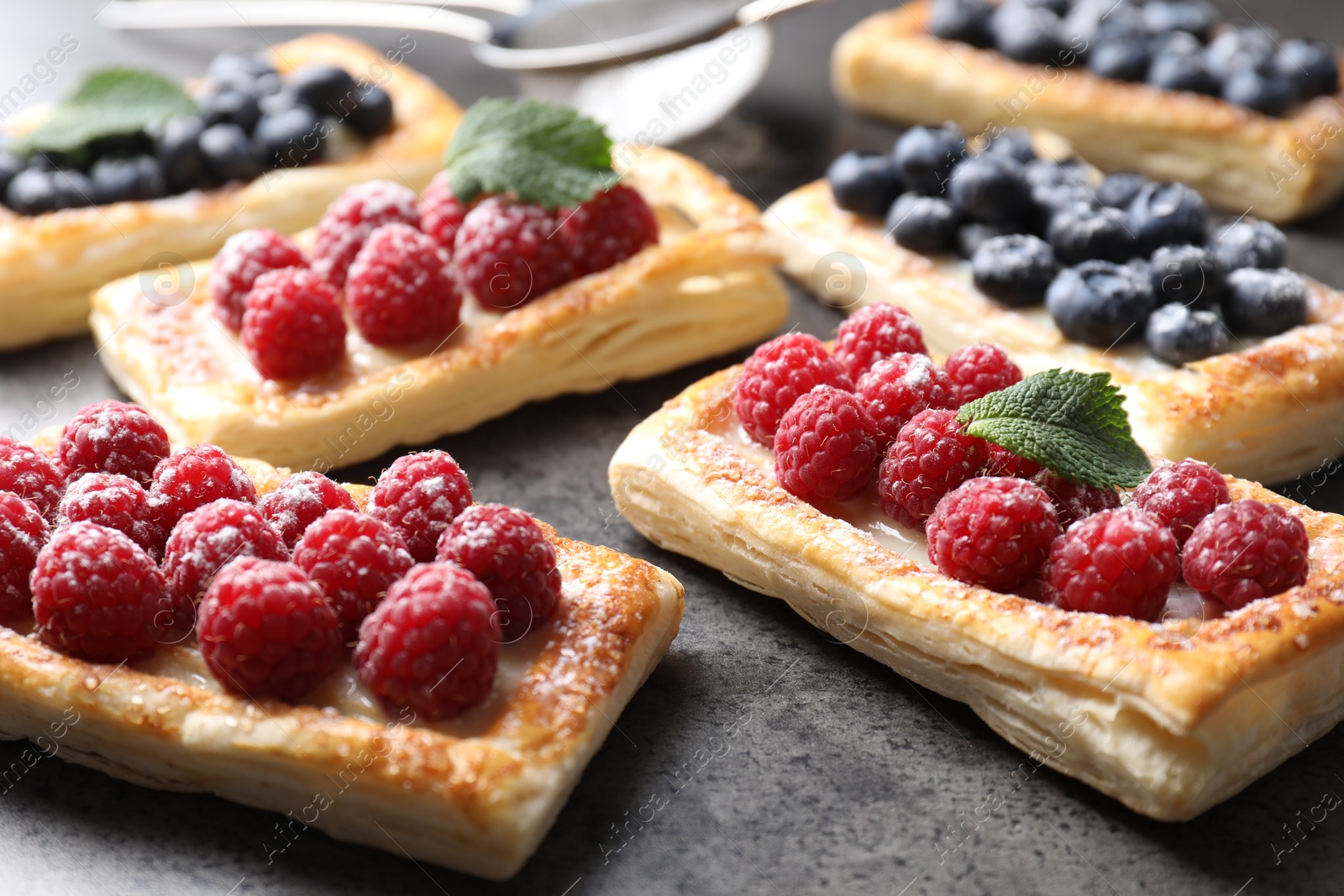 Photo of Tasty puff pastries with berries on grey table, closeup