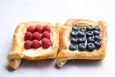 Photo of Tasty puff pastries with berries on white table, closeup