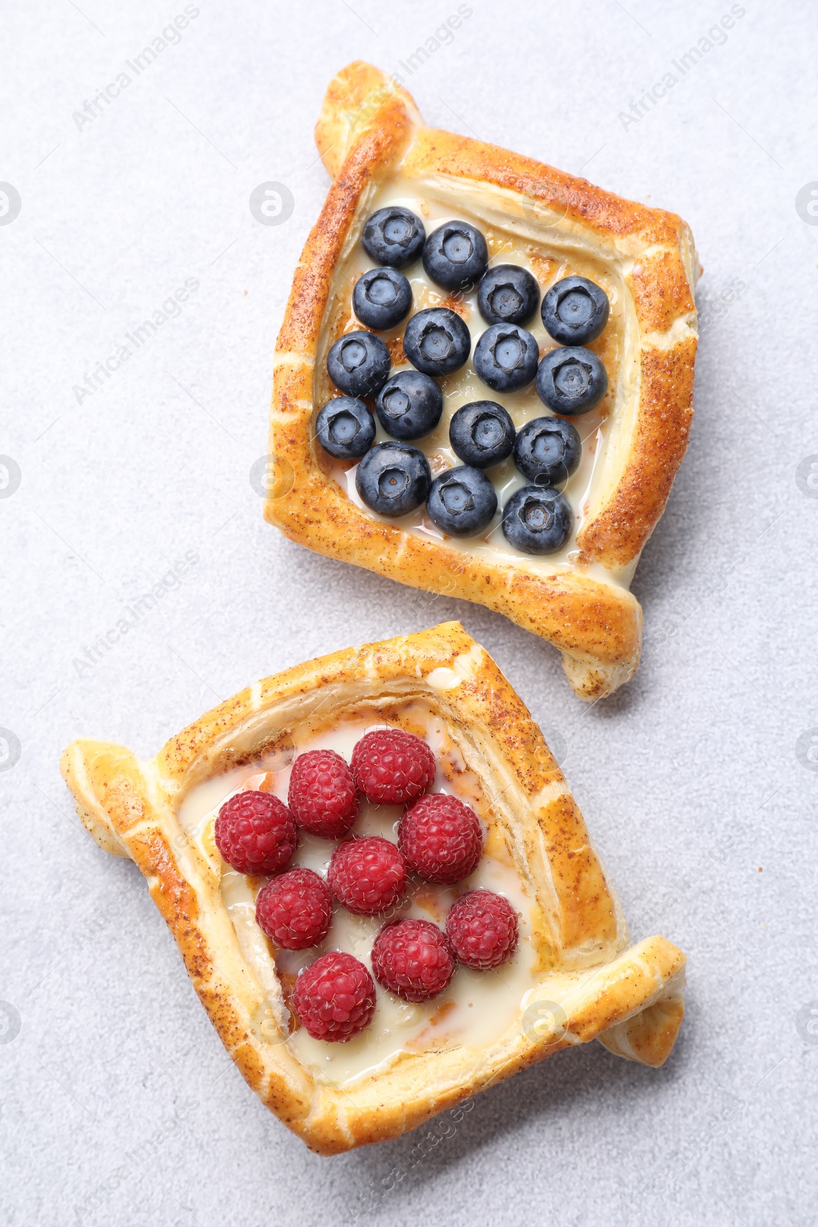 Photo of Tasty puff pastries with berries on white table, top view