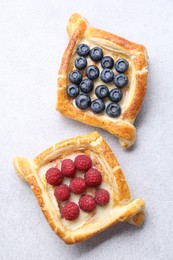 Photo of Tasty puff pastries with berries on white table, top view