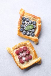 Photo of Tasty puff pastries with berries on white table, top view