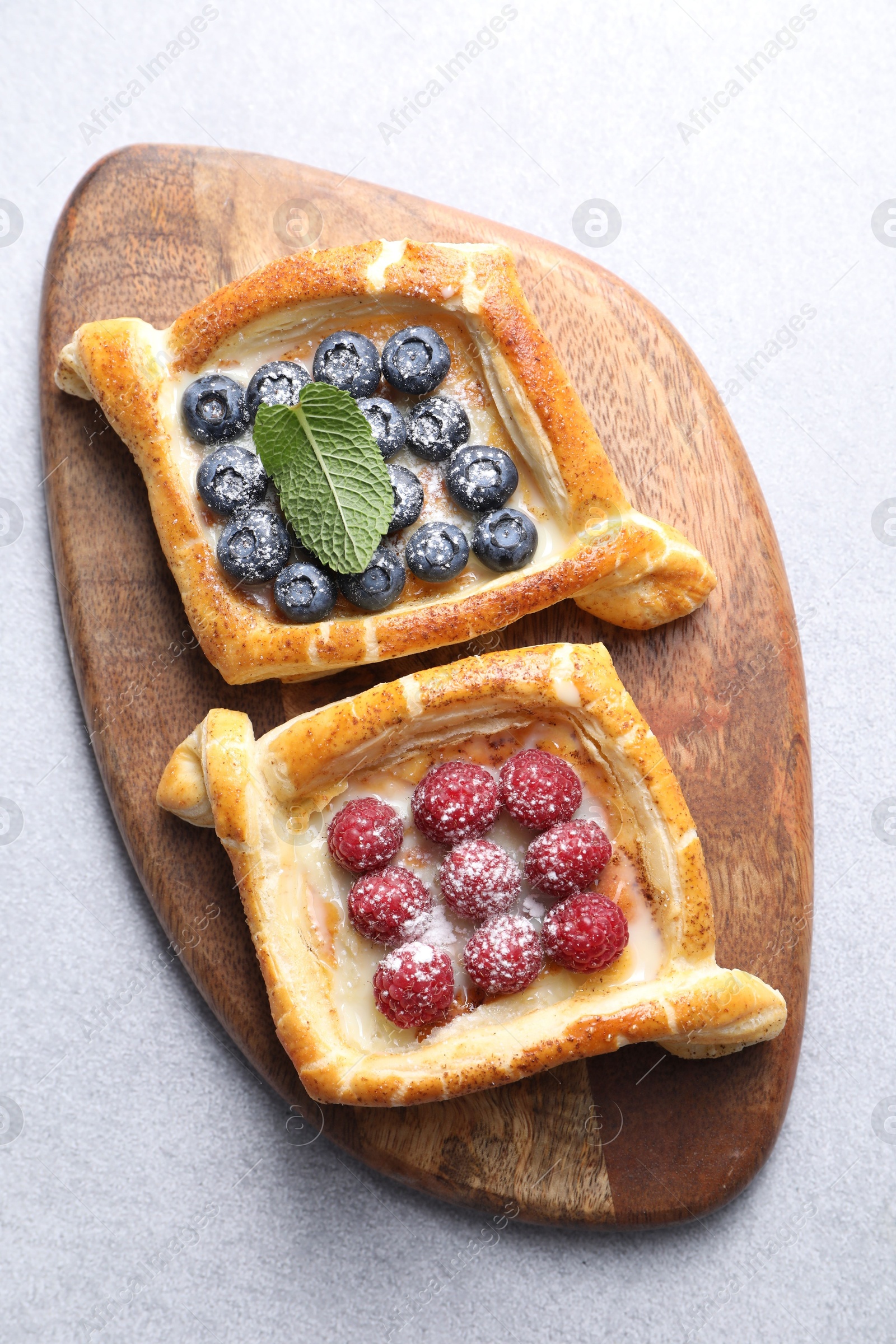 Photo of Tasty puff pastries with berries on white table, top view