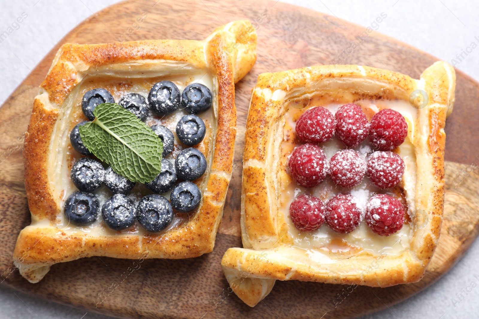 Photo of Tasty puff pastries with berries on white table, top view