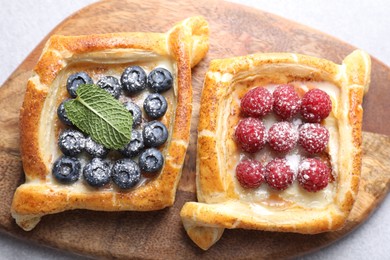 Tasty puff pastries with berries on white table, top view