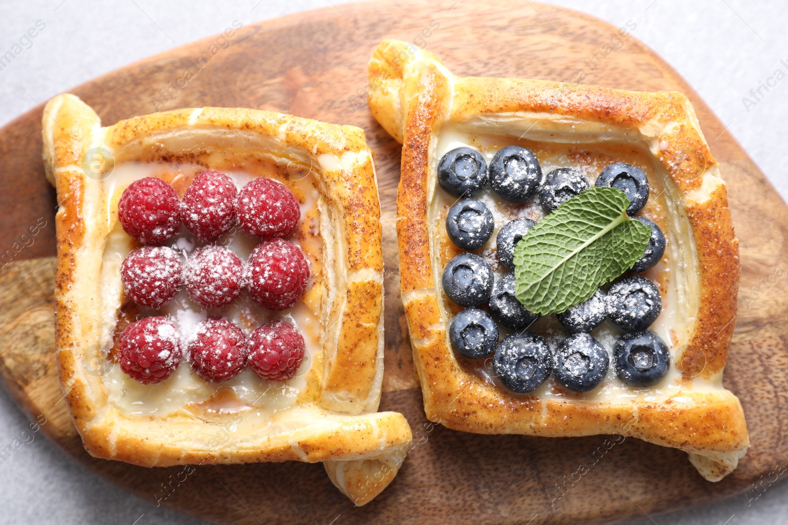 Photo of Tasty puff pastries with berries on white table, top view