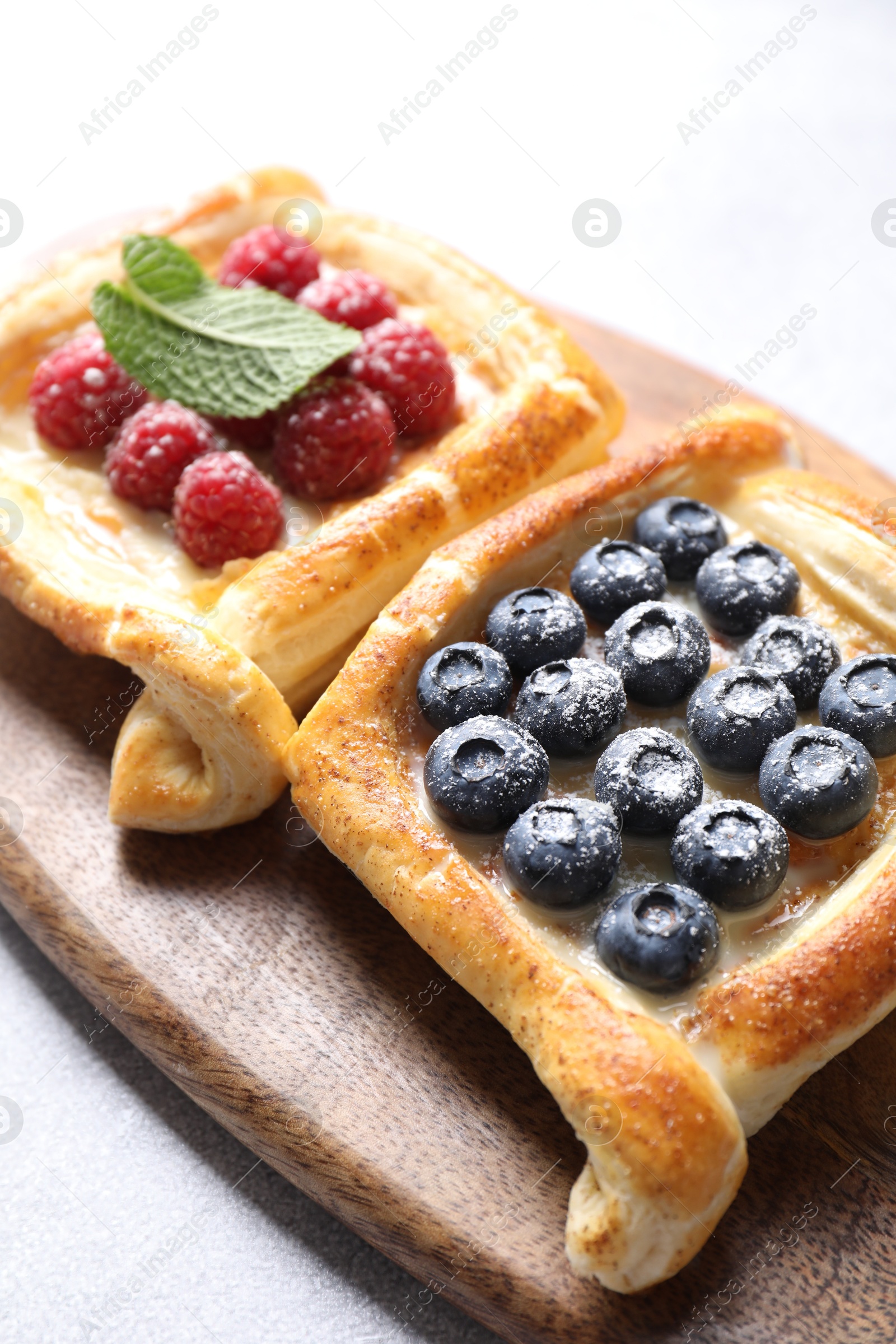 Photo of Tasty puff pastries with berries on white table, closeup