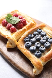 Tasty puff pastries with berries on white table, closeup