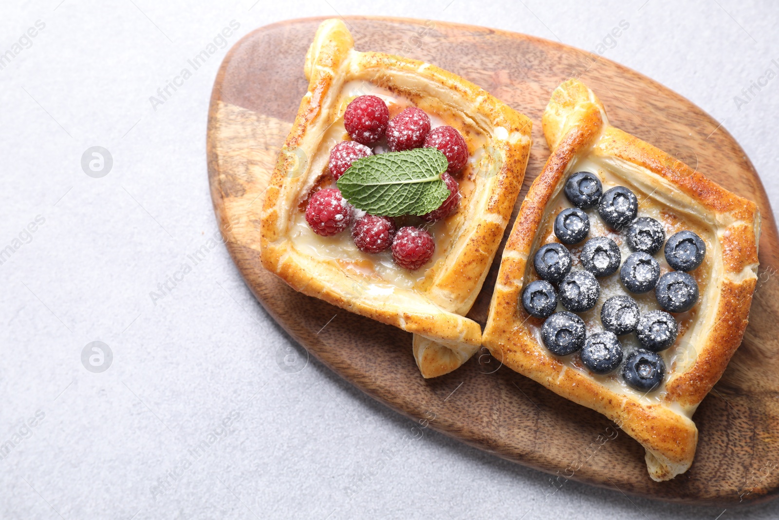 Photo of Tasty puff pastries with berries on white table, top view. Space for text