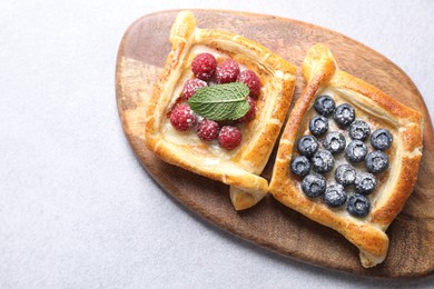 Tasty puff pastries with berries on white table, top view. Space for text