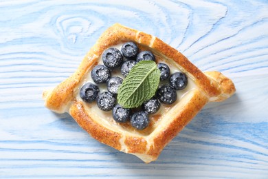 Photo of Tasty puff pastry with blueberries and mint on light blue wooden table, top view