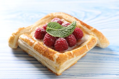 Tasty puff pastry with raspberries and mint on light blue wooden table