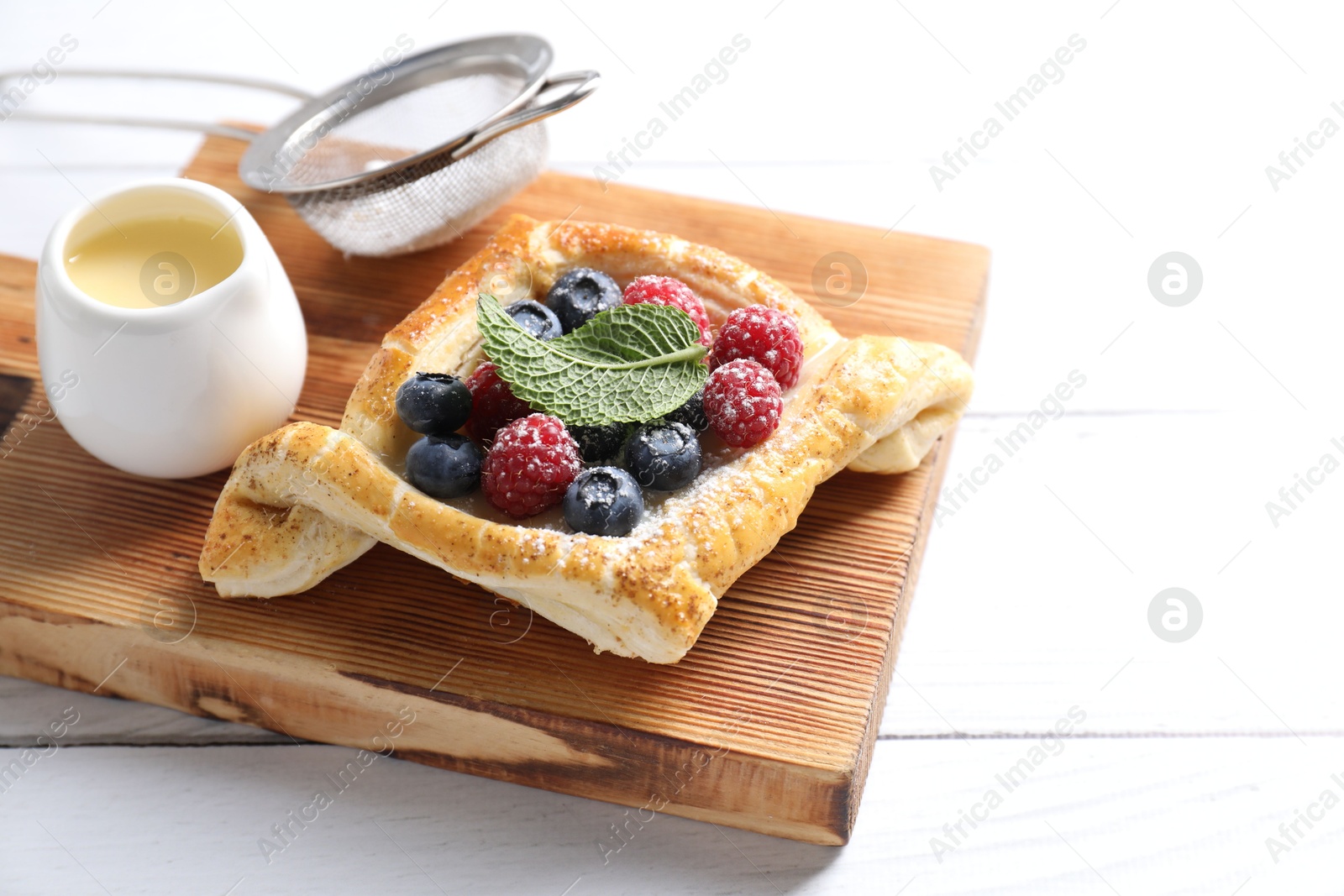 Photo of Tasty puff pastry with berries on white wooden table, space for text