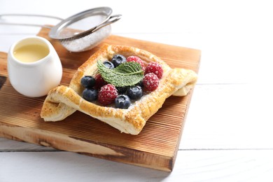 Photo of Tasty puff pastry with berries on white wooden table, space for text