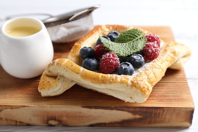 Tasty puff pastry with berries on white wooden table, closeup