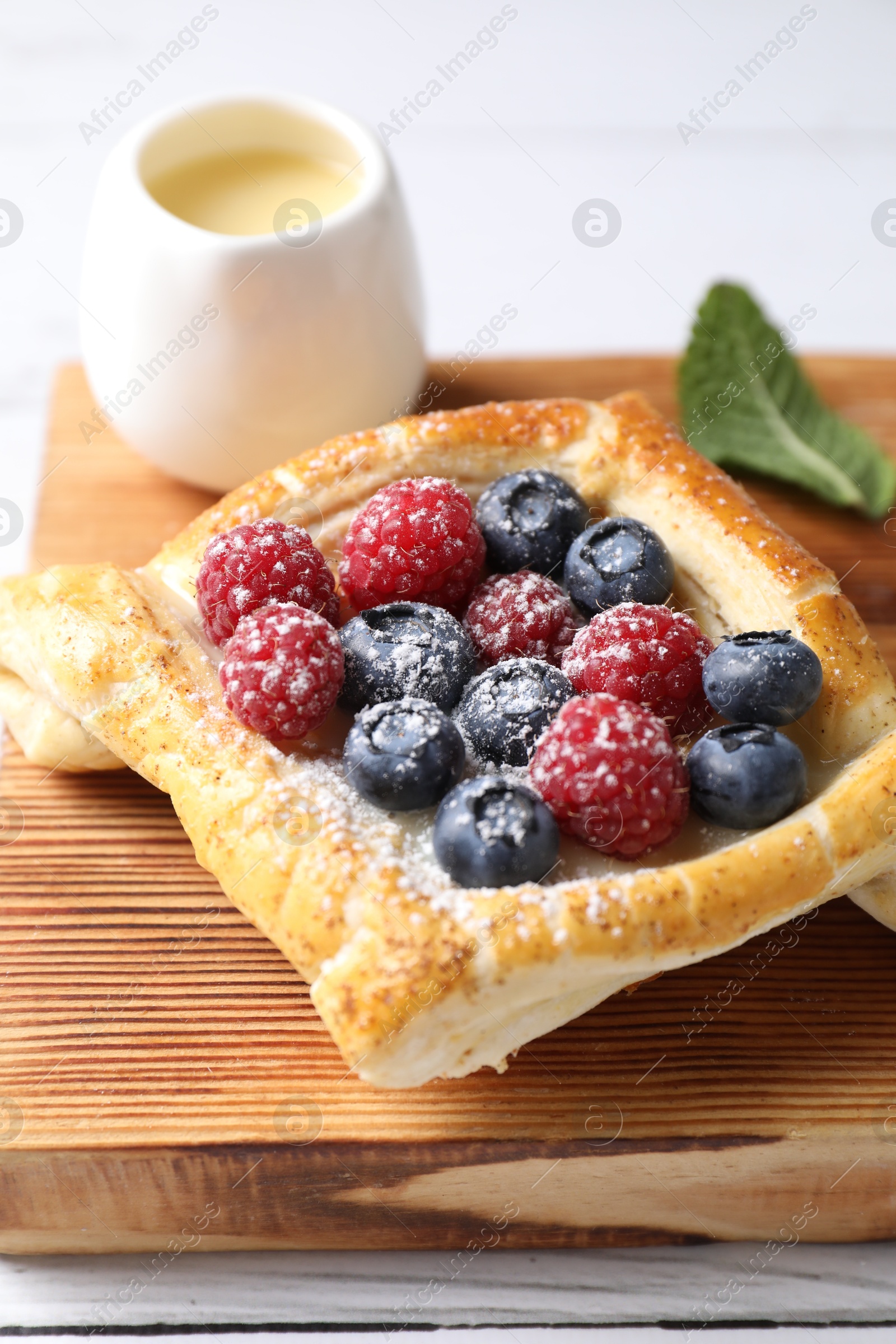 Photo of Tasty puff pastry with berries on white wooden table, closeup