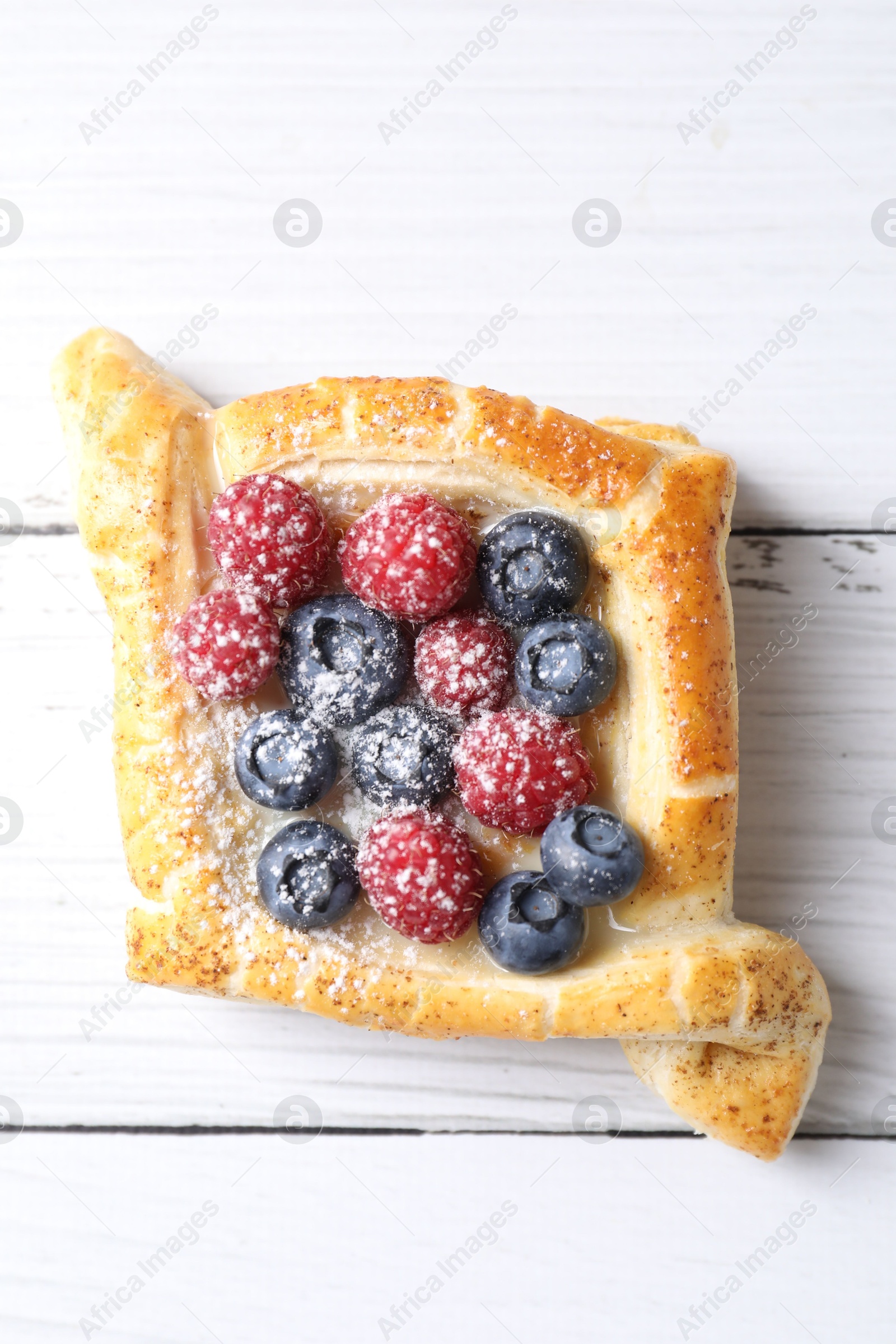 Photo of Tasty puff pastry with berries on white wooden table, top view