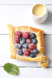 Photo of Tasty puff pastry with berries on white wooden table, top view