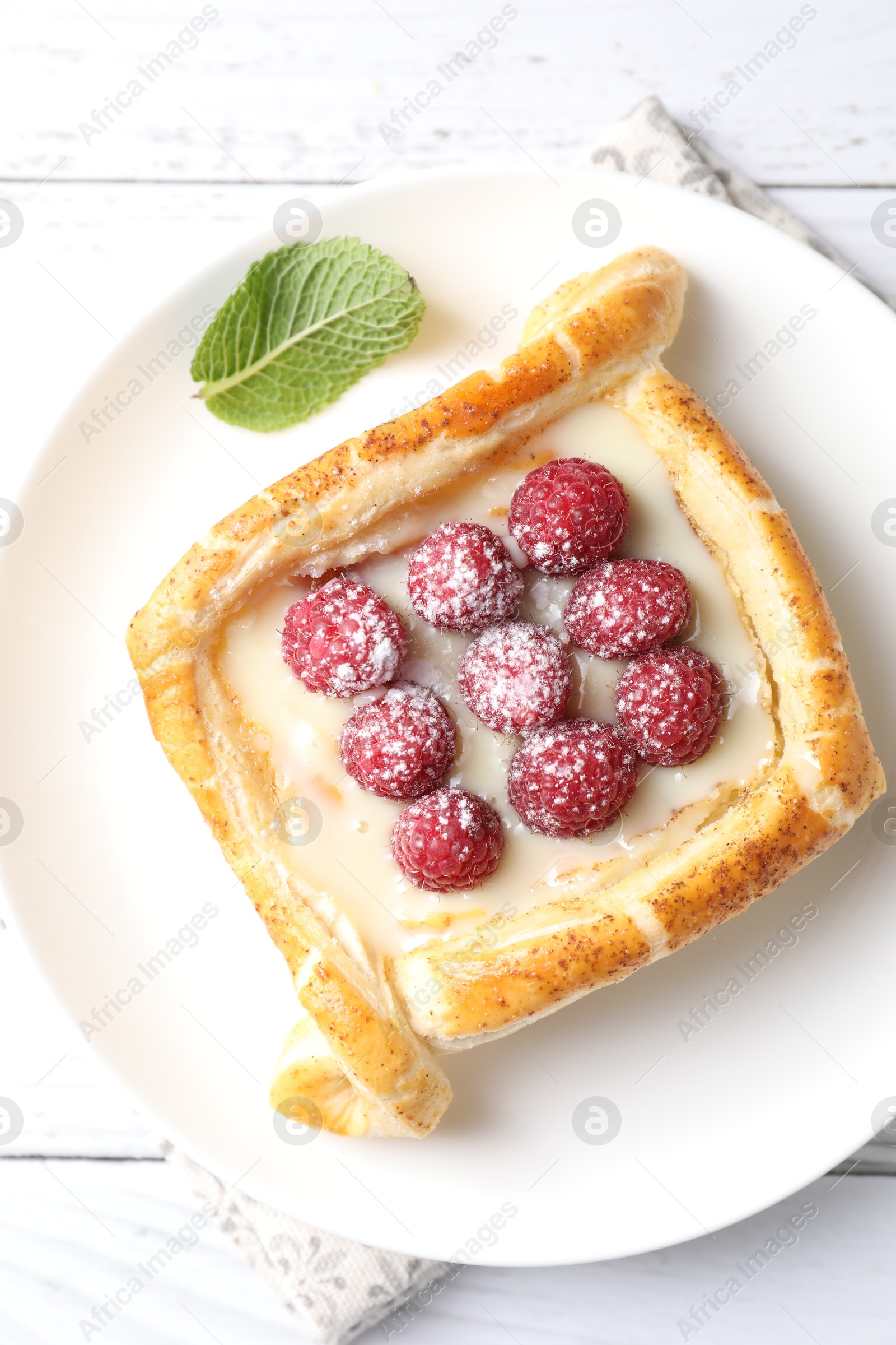 Photo of Tasty puff pastry with raspberries on white wooden table, top view