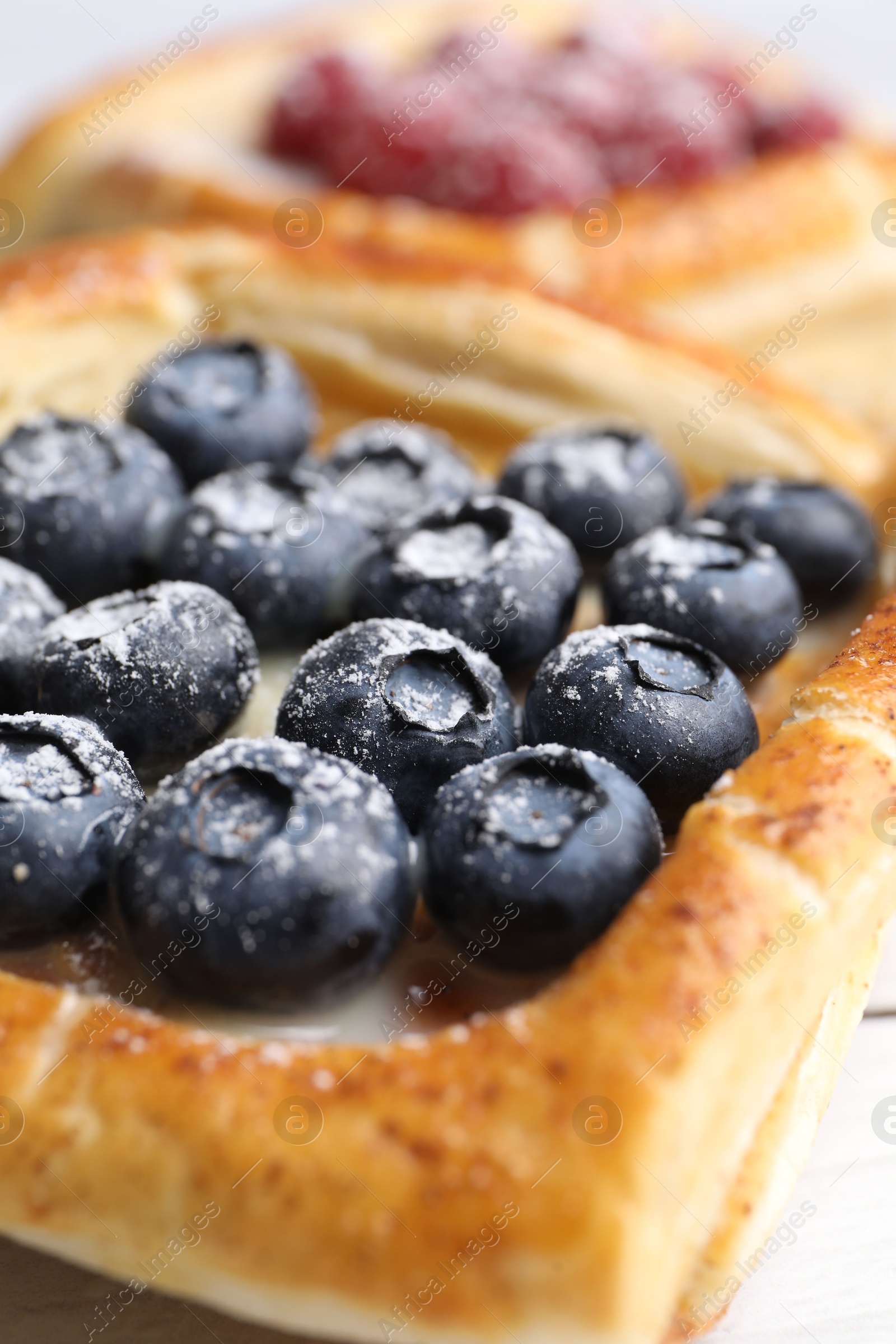 Photo of Tasty puff pastries with berries on table, closeup