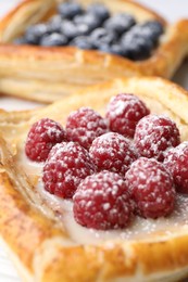 Tasty puff pastries with berries on table, closeup