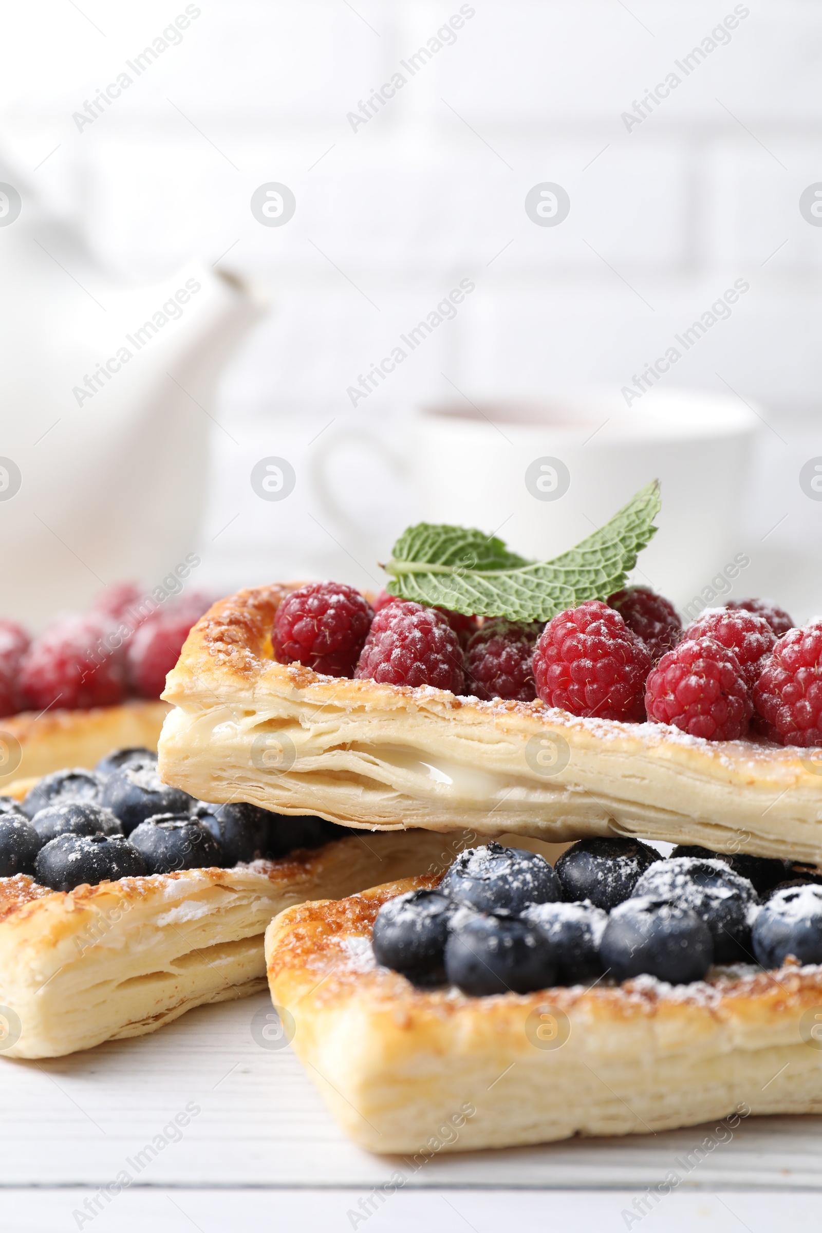 Photo of Tasty puff pastries with berries on white wooden table, closeup