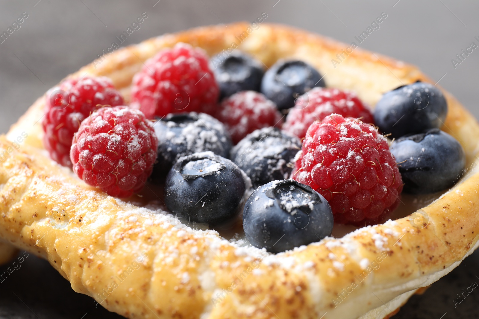 Photo of Tasty puff pastry with berries on grey table, closeup