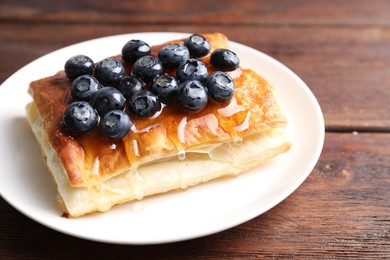 Tasty puff pastry with blueberries on wooden table, closeup