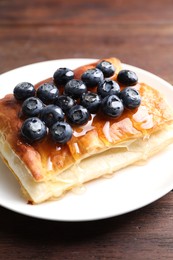 Photo of Tasty puff pastry with blueberries on wooden table, closeup