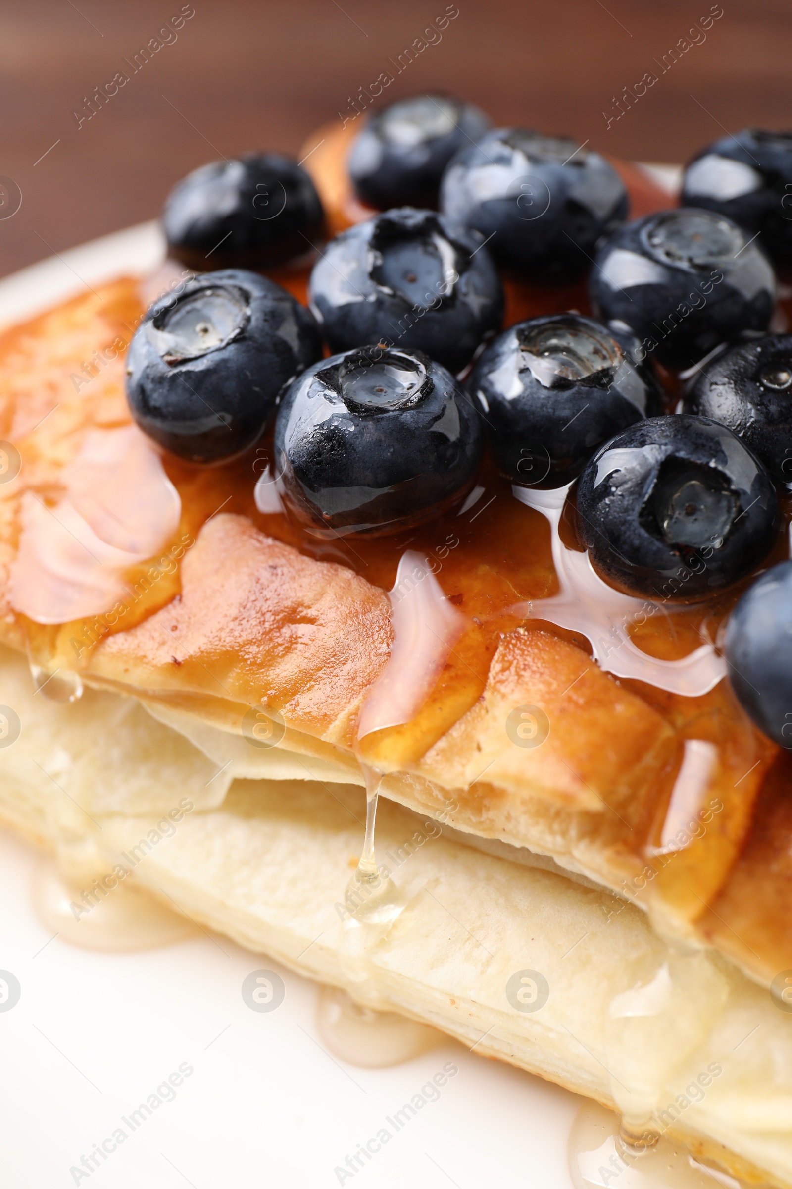 Photo of Tasty puff pastry with blueberries on wooden table, closeup