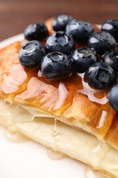 Tasty puff pastry with blueberries on wooden table, closeup