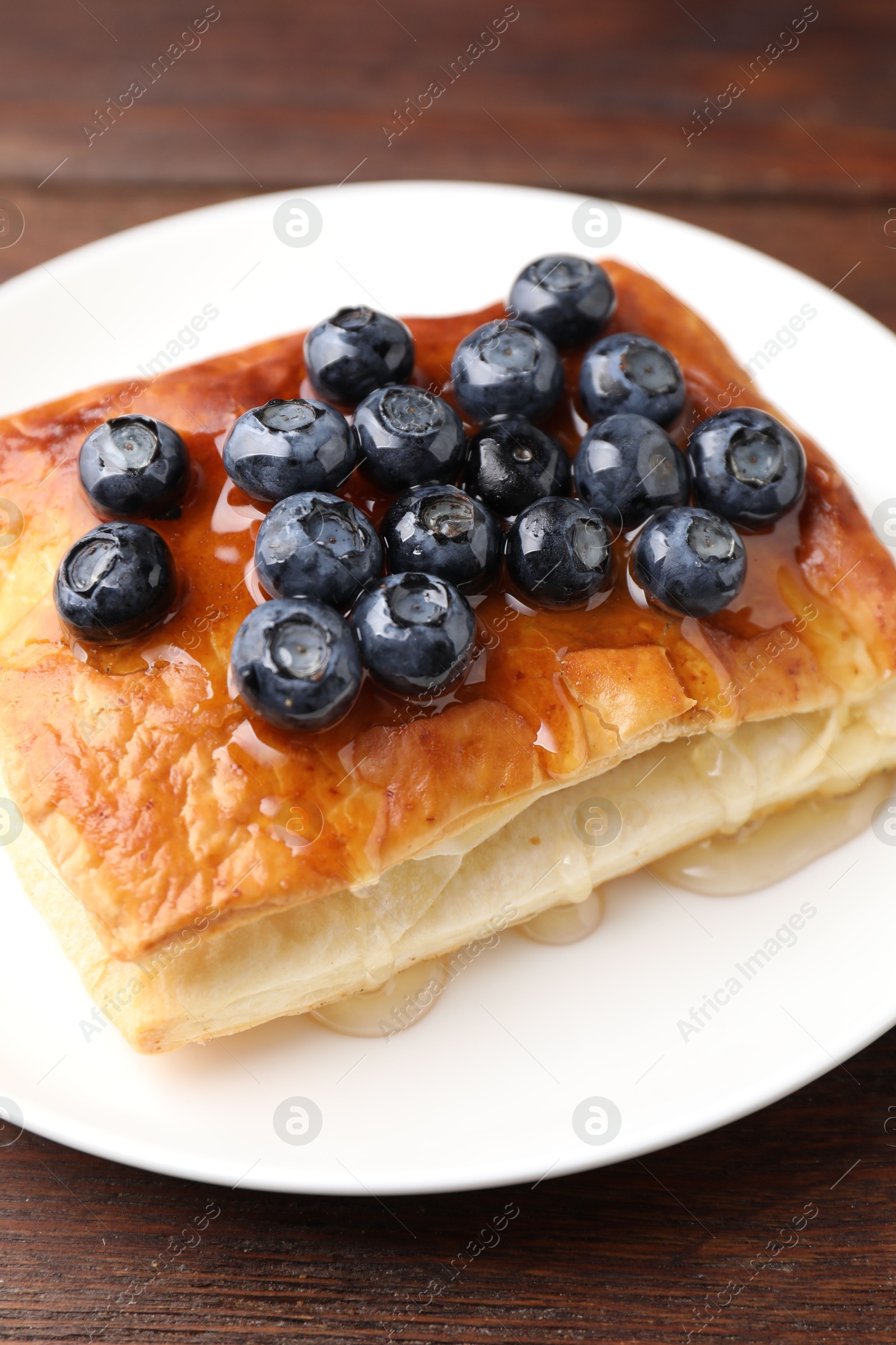 Photo of Tasty puff pastry with blueberries on wooden table, closeup