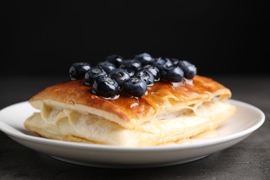 Photo of Tasty puff pastry with blueberries on grey table, closeup