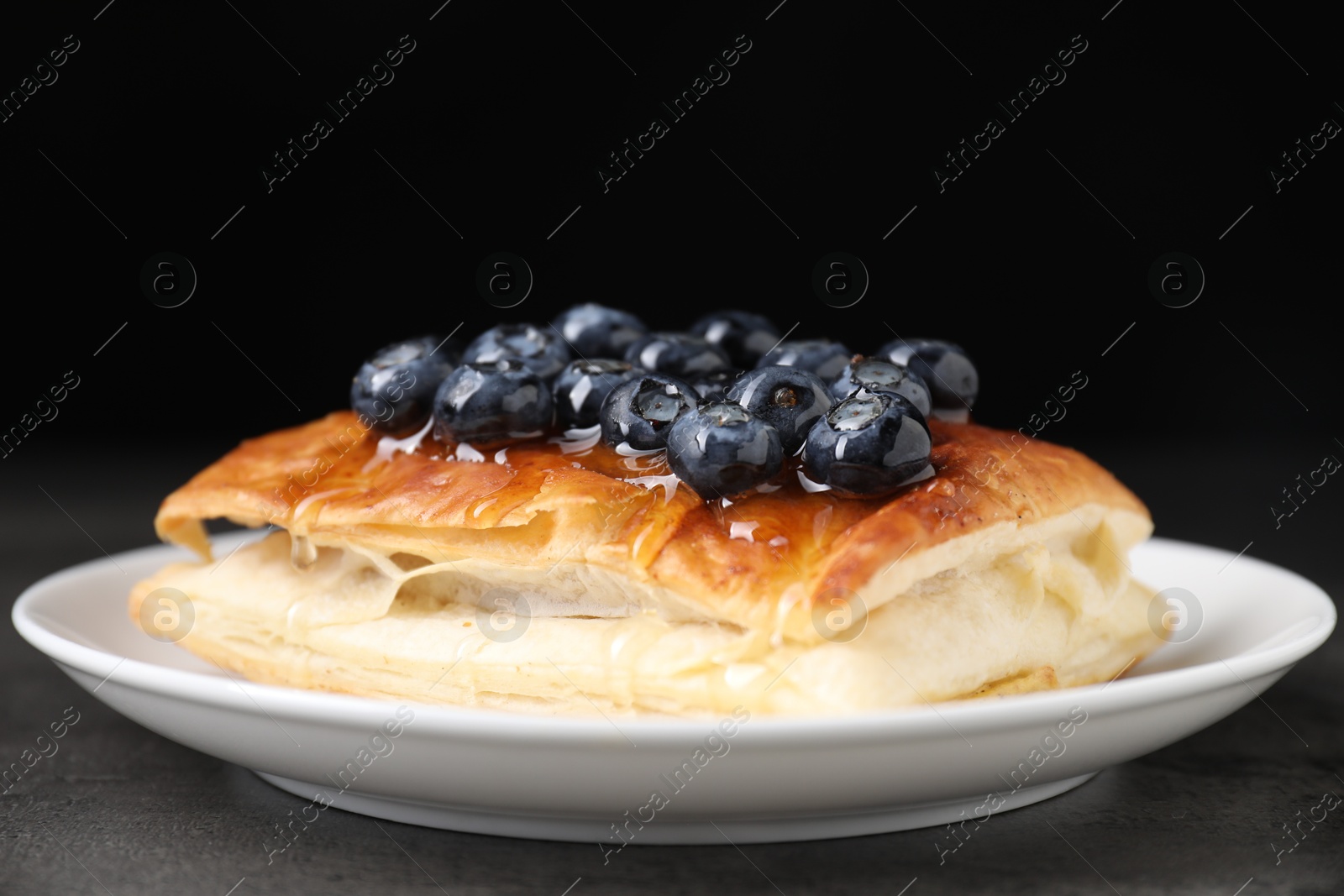 Photo of Tasty puff pastry with blueberries on grey table, closeup