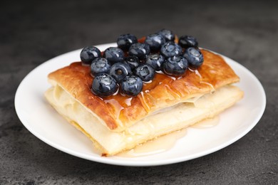 Tasty puff pastry with blueberries on grey table, closeup