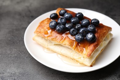 Photo of Tasty puff pastry with blueberries on grey table, closeup