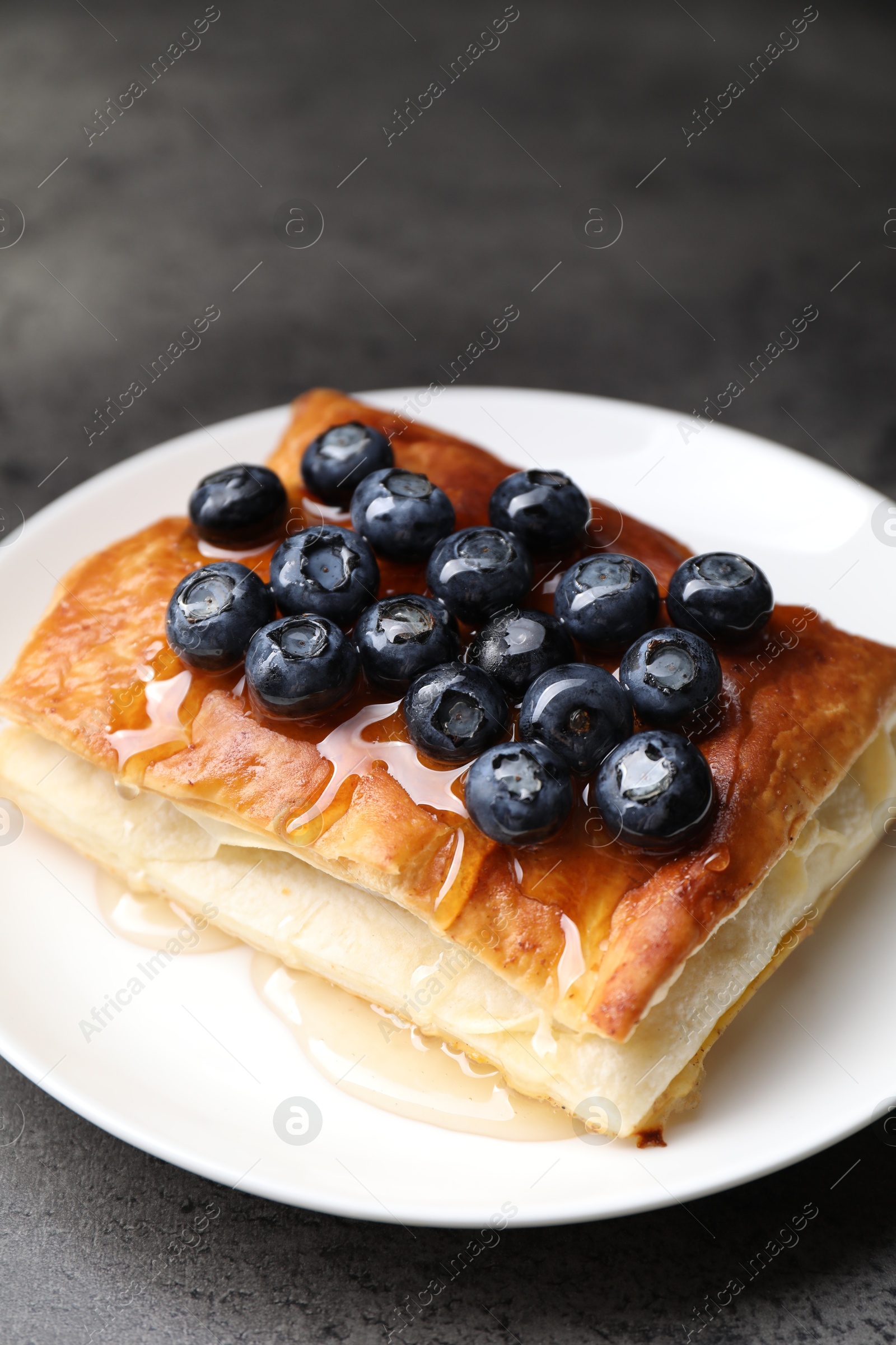 Photo of Tasty puff pastry with blueberries on grey table, closeup