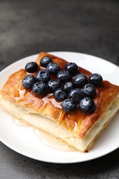 Photo of Tasty puff pastry with blueberries on grey table, closeup