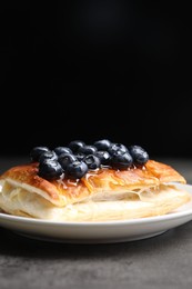 Photo of Tasty puff pastry with blueberries on grey table, closeup. Space for text