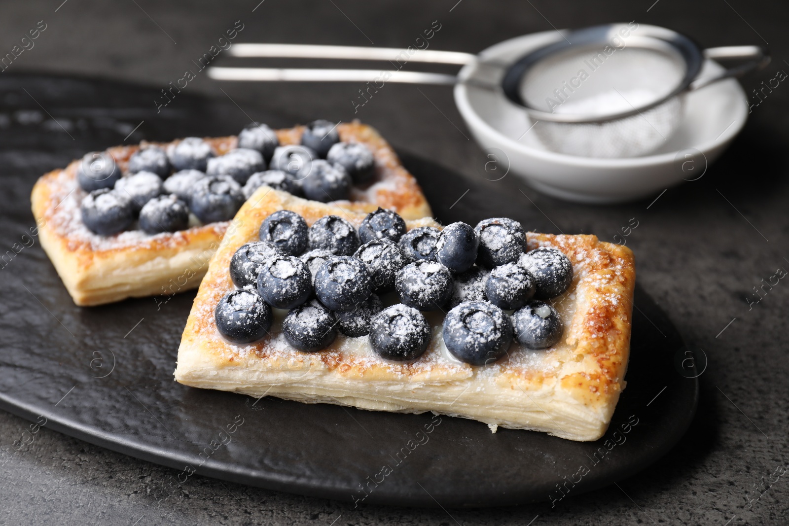 Photo of Tasty puff pastries with blueberries on grey table, closeup