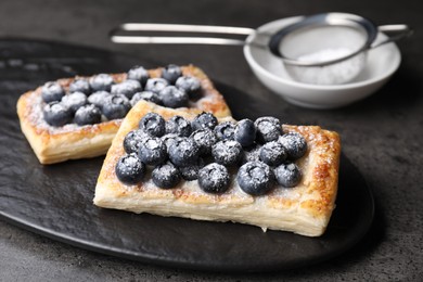 Photo of Tasty puff pastries with blueberries on grey table, closeup