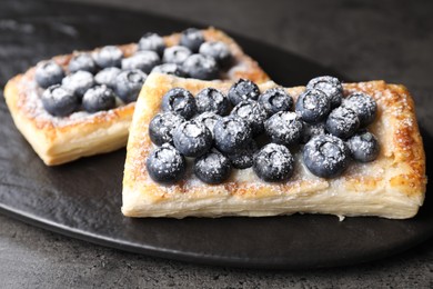 Photo of Tasty puff pastries with blueberries on grey table, closeup