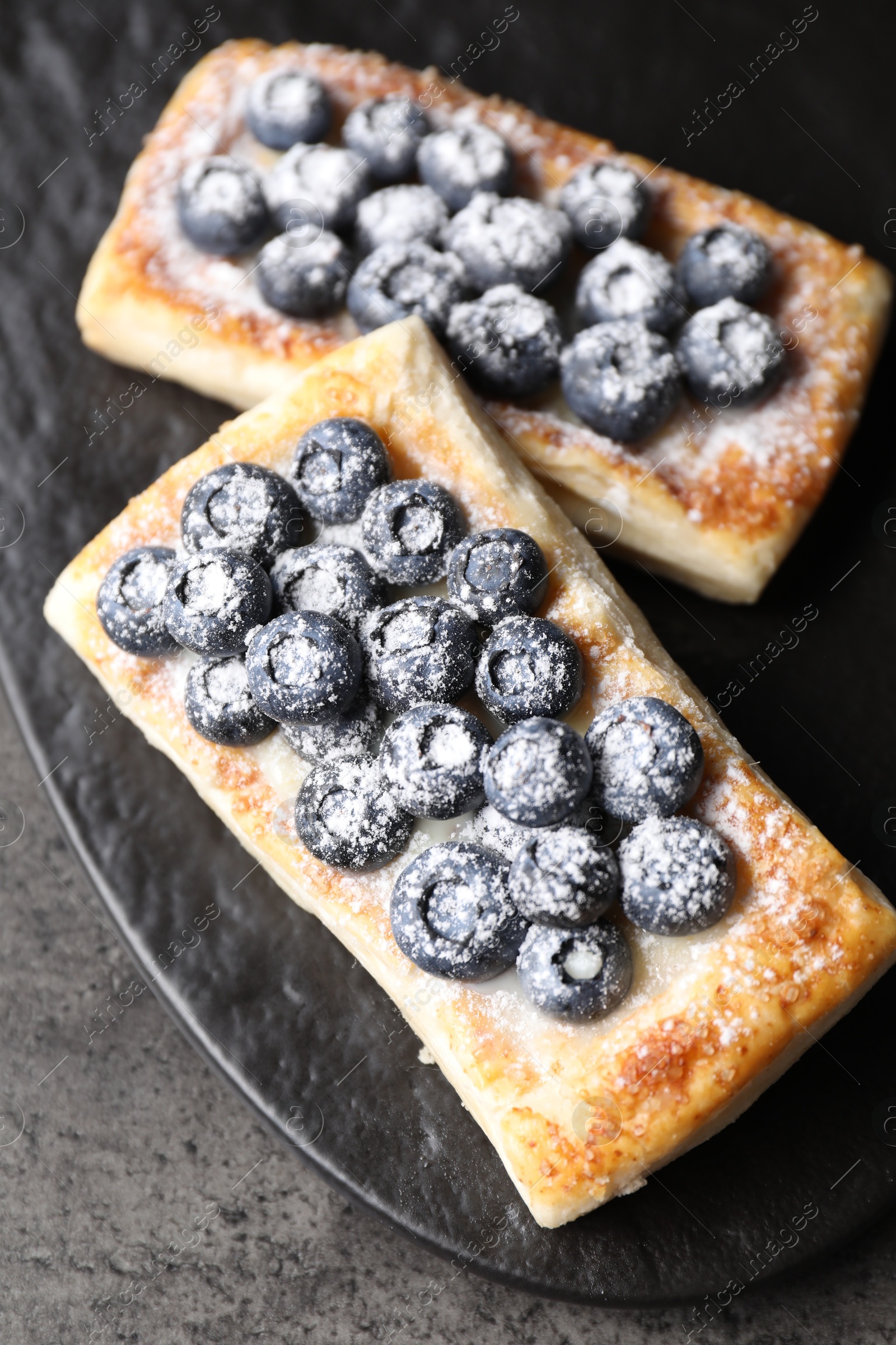 Photo of Tasty puff pastries with blueberries on grey table