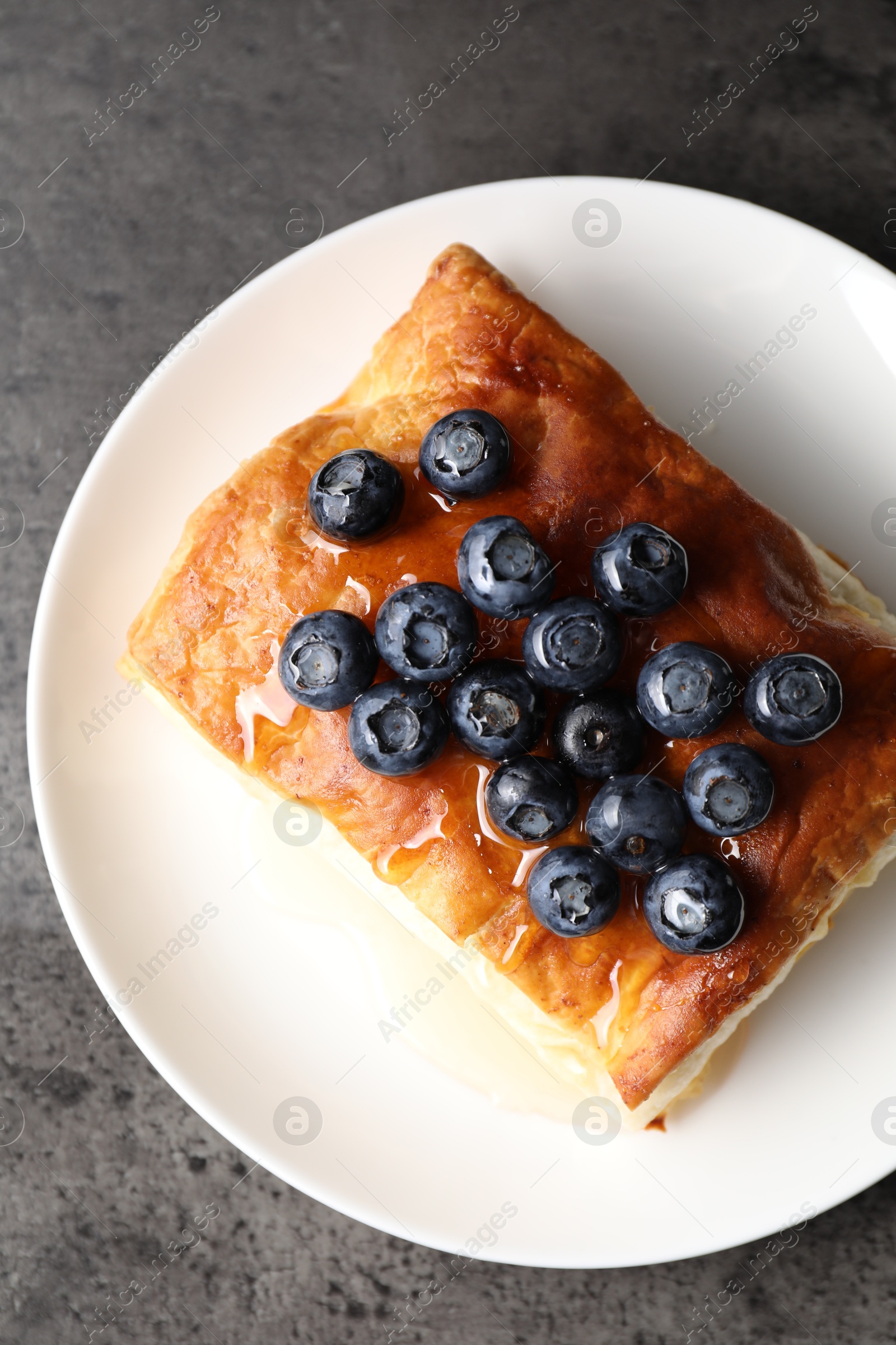 Photo of Tasty puff pastry with blueberries on grey table, top view