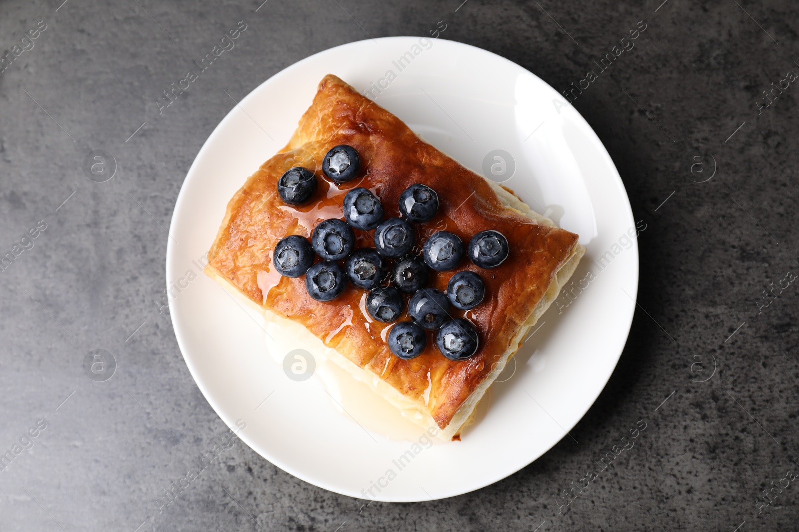 Photo of Tasty puff pastry with blueberries on grey table, top view