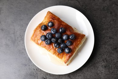 Photo of Tasty puff pastry with blueberries on grey table, top view