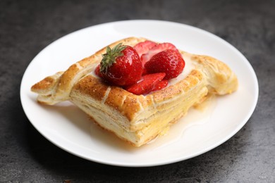 Tasty puff pastry with strawberries on grey table, closeup