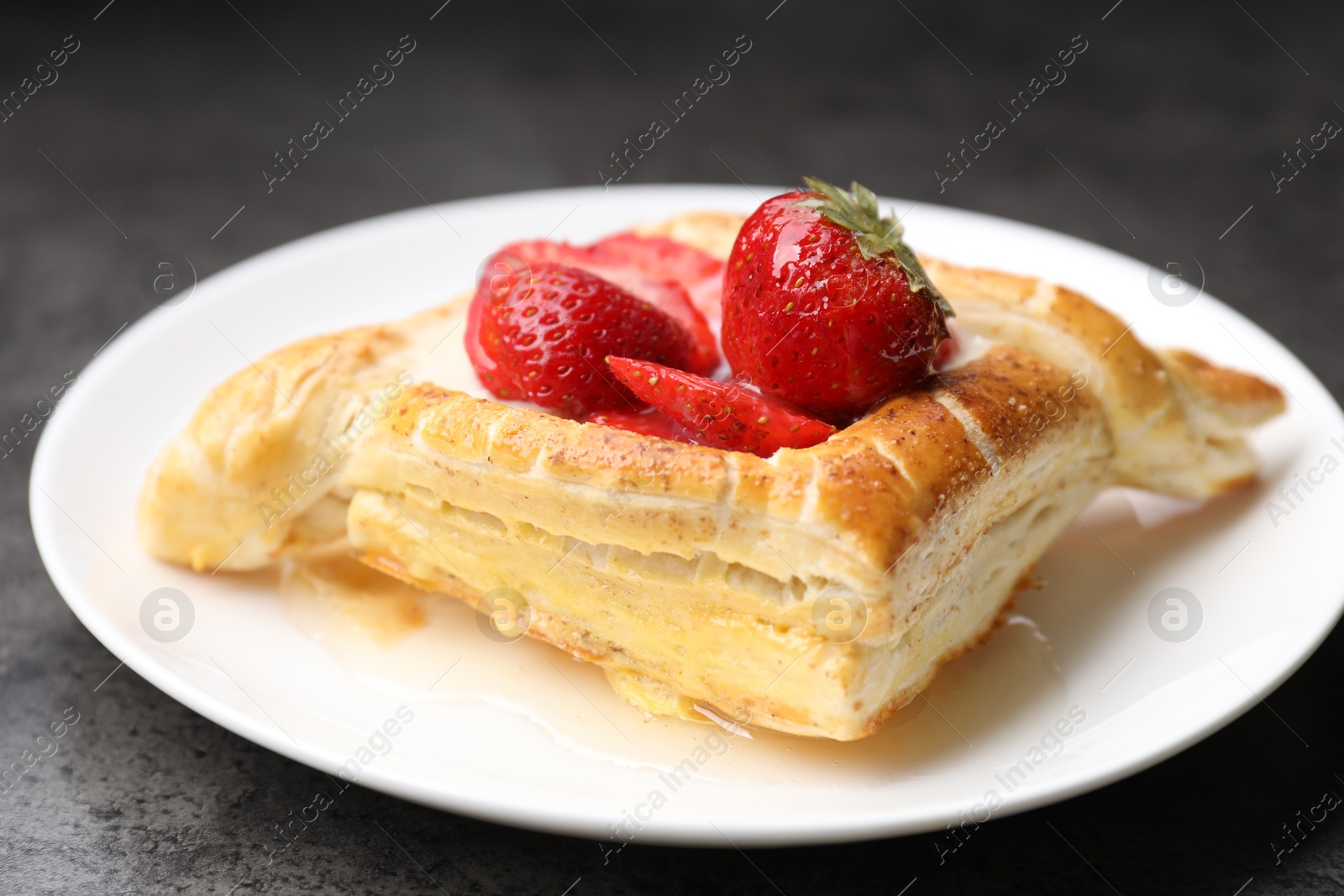 Photo of Tasty puff pastry with strawberries on grey table, closeup