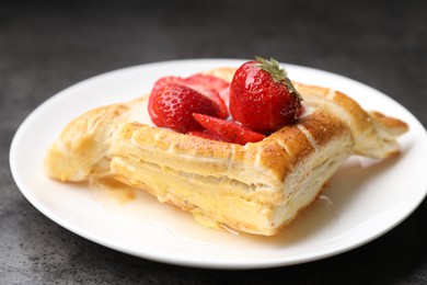 Tasty puff pastry with strawberries on grey table, closeup